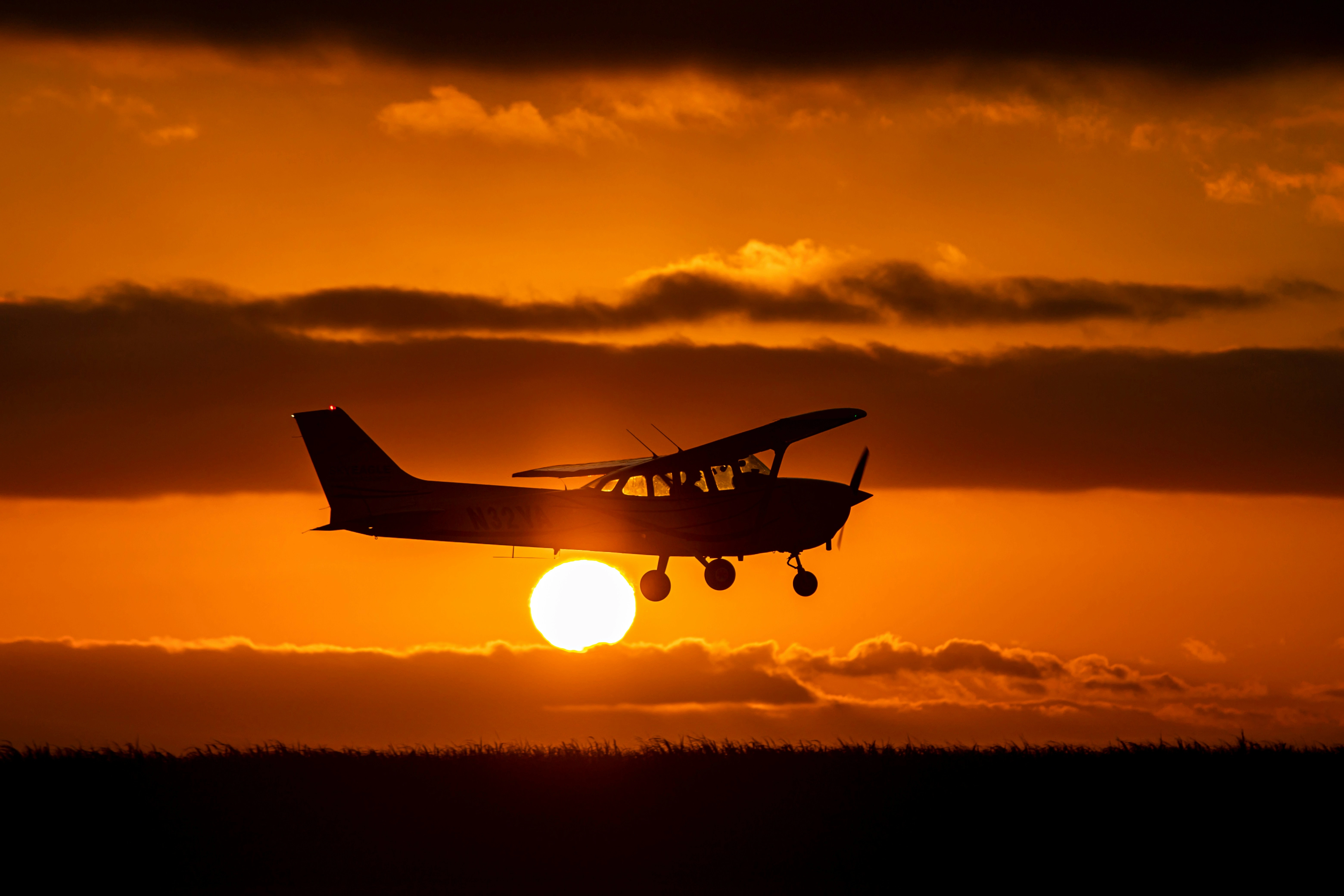 A small aircraft flying over a scenic landscape during sunset.